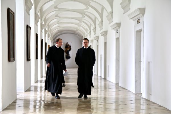Zwei Mönche unterhalten sich beim gemeinsamen Spaziergang im Stiftsflur