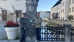 Zwei Schüler vor einem Wassergraben zeigen auf einen QR-Code