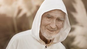 Porträt von Bruder David Steindl Rast, mit grauem Bart, weißer Jacke und weißer Kaputze