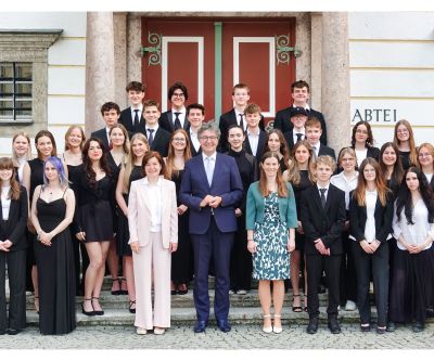 Maturantinnen und Maturanten festlich gekleidet vor einem Portal