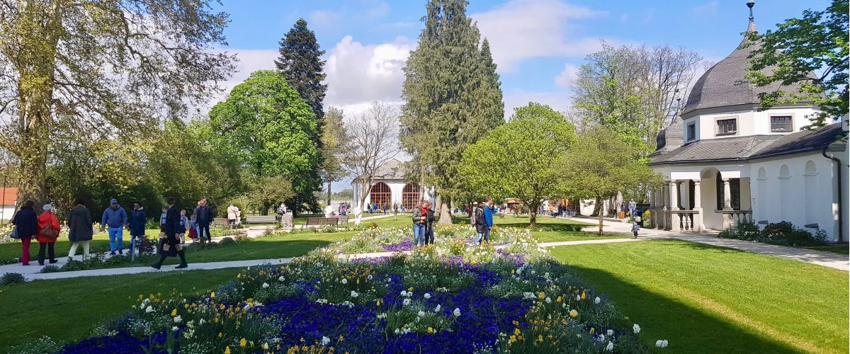 Frühling im Stiftsgarten: viele Menschen spazieren auf den weißen Kieswegen durch die blühenden Blumenbeete