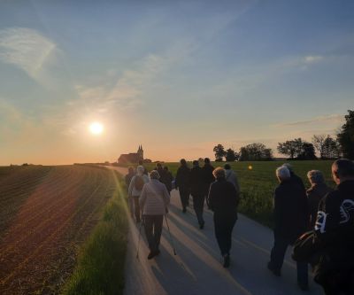 Gruppe von Personen, die bei Sonnenuntergang zu einer Kirche wandert