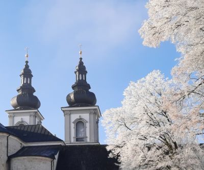 Zwei Kirchturmspitzen, blauer Himmel, winterliche Bäume